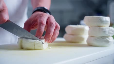un chef cortando queso en la cocina con un cuchillo
