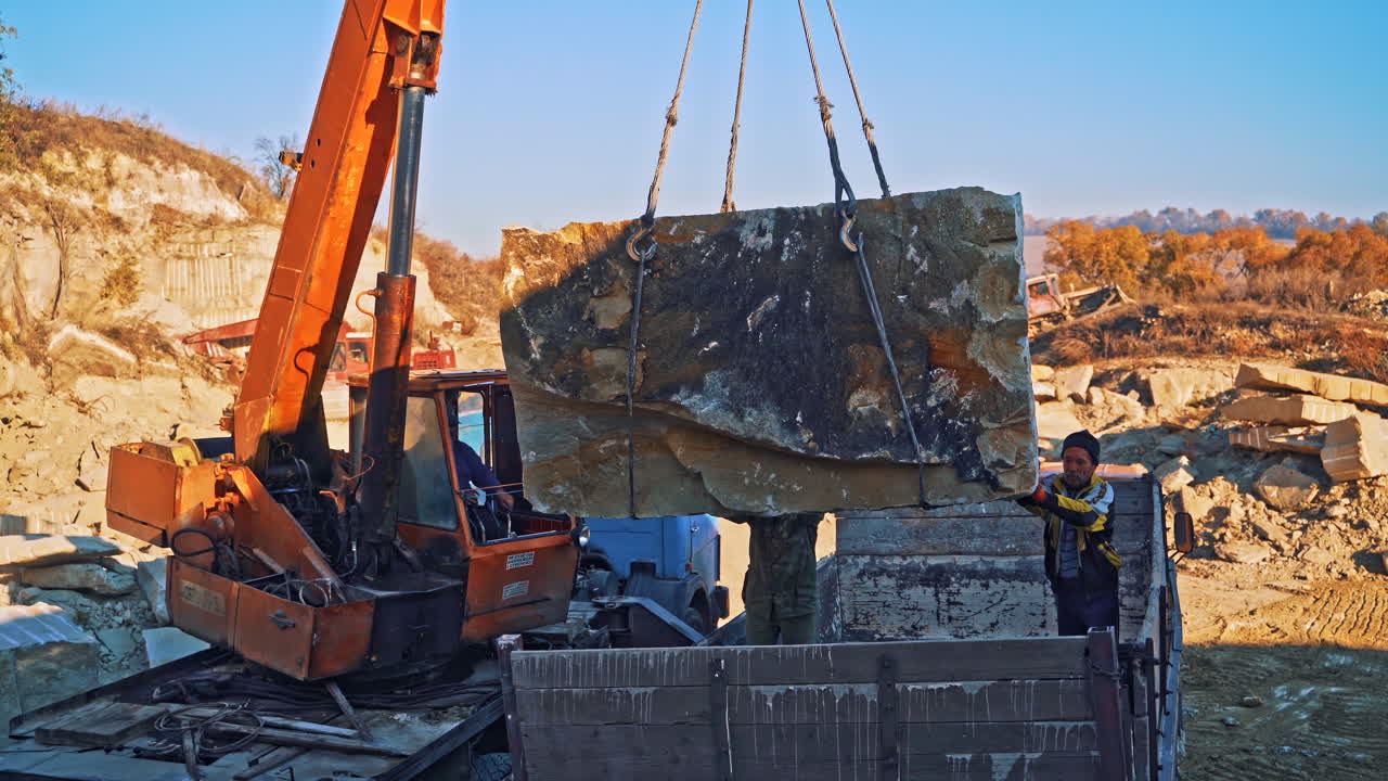 Block suspended on crane hook. Marble quarry with old crane on mining site
