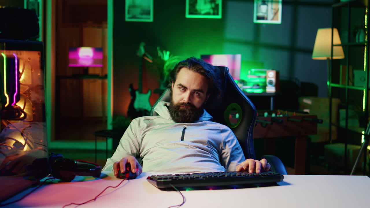 Man obsessed with playing videogames all day falling asleep at computer desk