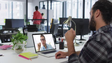 hombre de oriente medio teniendo una videollamada con un colega masculino en una computadora portátil en la oficina