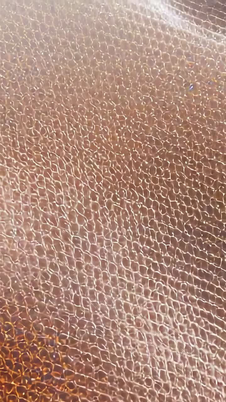 Video verticale: luce in movimento che mostra da vicino la superficie marrone per lo studio della texture, striature lucide