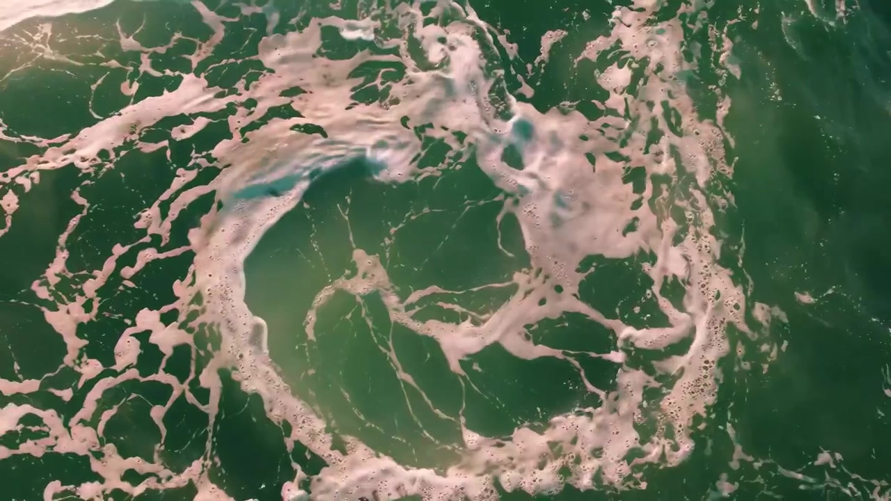Aerial View of Ocean Waves Crashing and Creating Sea Foam