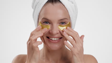 woman applying gold eye patches