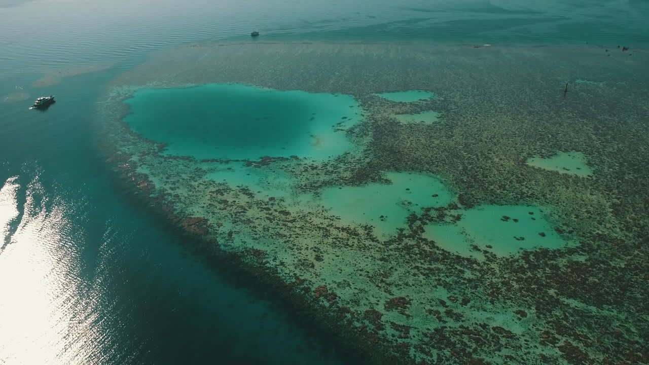Ripresa aerea del Mar Rosso egiziano a nord, vicino a Hurghada, con il drone che avanza verso un faro su un'isola corallina di Abu Nuhas