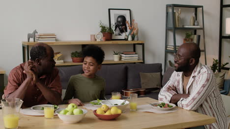 black men and boy eating lunch at home