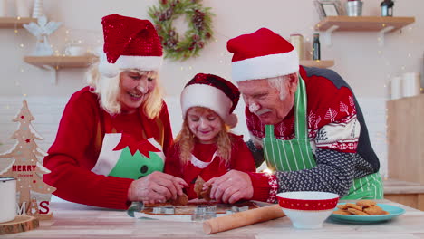 Senior-family-grandparents-with-granddaughter-in-Santa-Claus-hats-preparing,-cooking-homemade-cookie