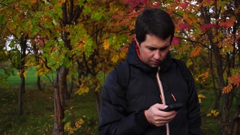 hombre usando teléfono inteligente en el parque de otoño