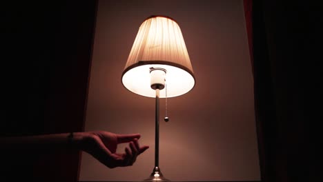 Close-up-shot-of-white-table-lamp-being-turned-off-with-a-male-hand