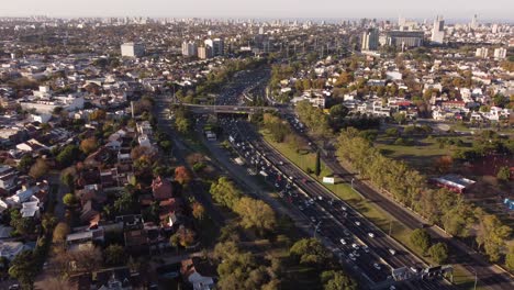 wide panoramic birds eye drone view of general paz busy highway and car traffic with buenos aires skyline in background and sky for copy space