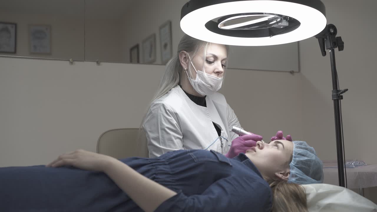 un cosmetólogo profesional hace maquillaje permanente en las cejas