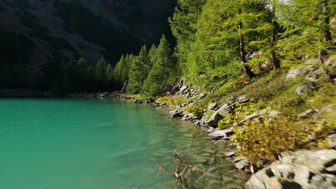 Let dronu nízko nad hladinou tyrkysového jezera Lagazzuolo ve Valmalencu, Italské Alpy. Letecký záběr vpřed.