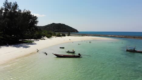 flying with drone over sandy beach and tourists at ao chaloklum bay in koh phangan, thailand