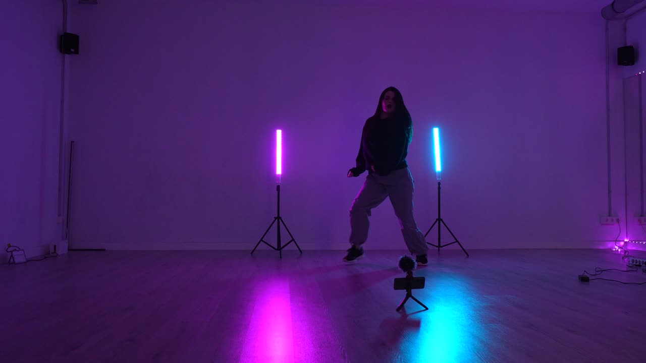 Donna che balla in uno studio illuminato al neon