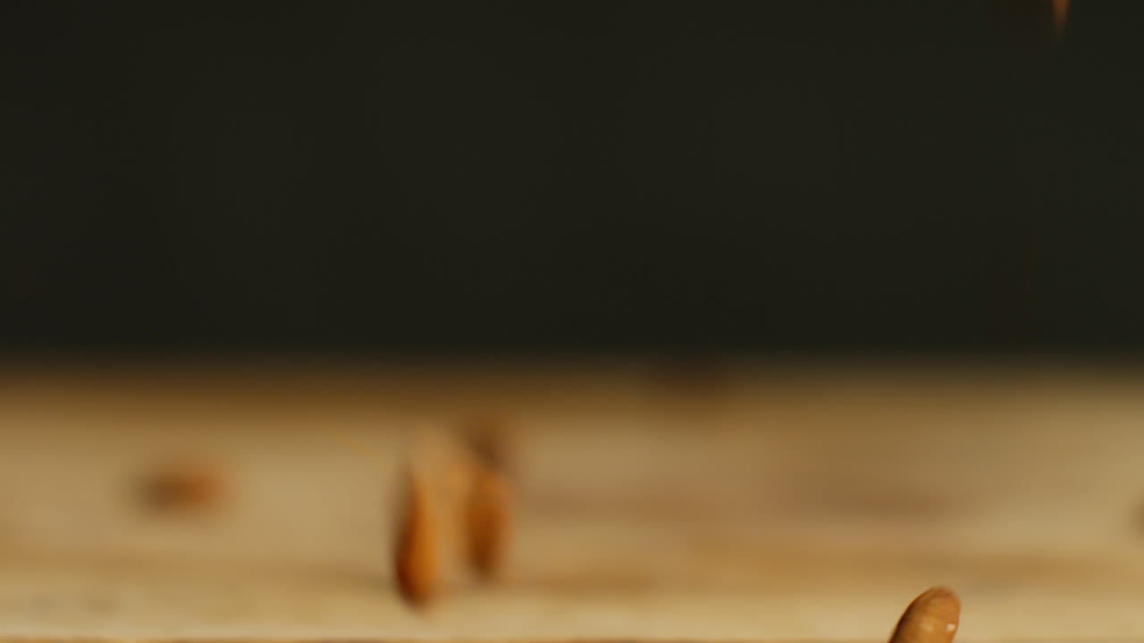 fotografía de cerca de nueces de almendra cayendo sobre una superficie de madera contra un fondo de estudio negro tomada en cámara lenta 1