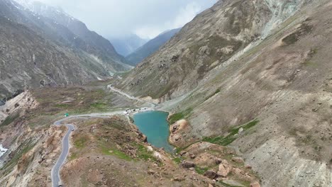 aerial drone shot capturing the serene waters of depak tal nestled amidst rugged mountain peaks.