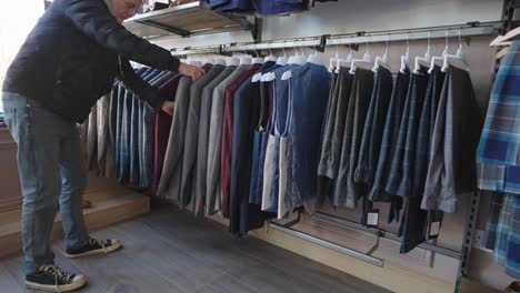 hombre en la tienda navegando a través de una fila de chaquetas kilt