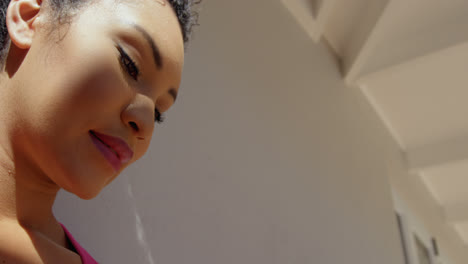 Low-angle-view-of-young-mixed-race-woman-using-mobile-phone-in-back-yard-of-home-4k