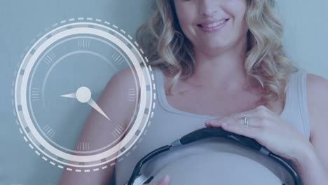 Clock-with-fast-moving-hands-over-happy-pregnant-caucasian-woman-with-headphones-on-belly