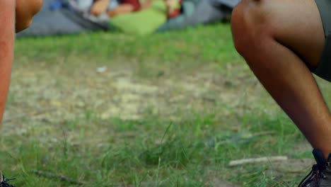 men roasting hot dog on campfire while women using mobile phone in tent 4k