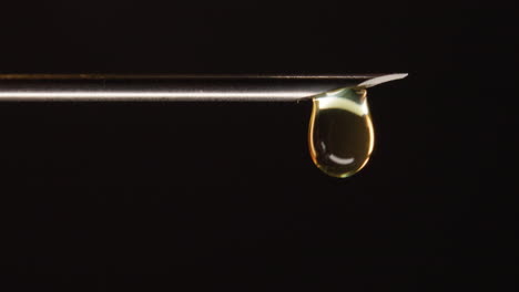 hypodermic needle dripping on dark background