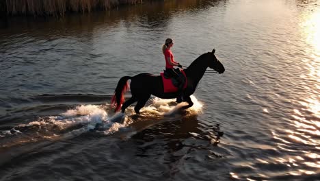 woman horseback riding in a river at sunset