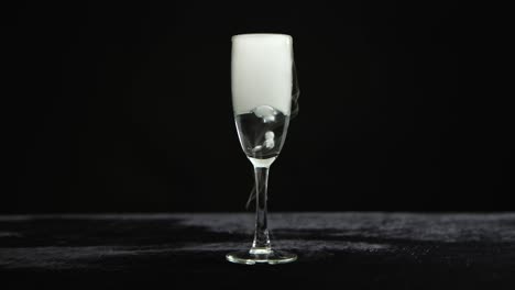champagne flute with dry ice smoke on black background