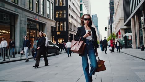 stylish woman walking on a city street while looking at her phone