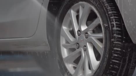 close up of washing a car tire with foam and pressurized water. car wash.