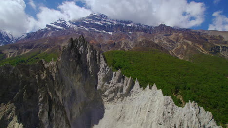 aerial view of muddy mountains in manang nepal surrounded by green hilly landscapes with huge forest