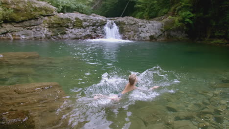 niño nadando en un arroyo de montaña con cascada