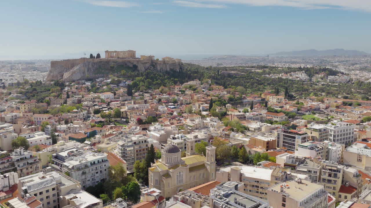 Ripresa aerea lenta con drone della Cattedrale metropolitana di Atene in una giornata di sole, con l'Acropoli e il Partenone sullo sfondo