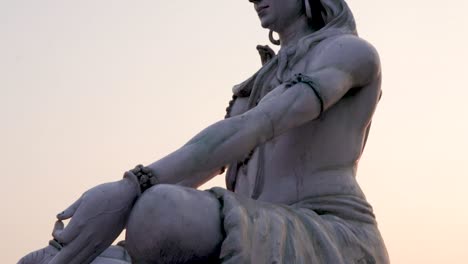 hindu god lord shiva statue in meditation posture with flat sky at evening from low angle video is taken at parmarth niketan rishikesh uttrakhand india on mar 15 2022