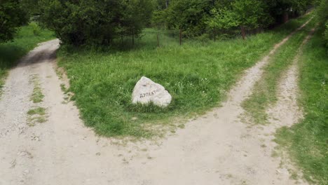 Drone-panning-from-the-left-to-the-right-over-a-natural-rock-landmark-in-the-middle-of-a-crossroad-in-a-wooded-area-in-Tsarichina-Hole-village-in-Bulgaria