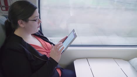 Side-View,-Young-professional-woman-uses-touchscreen-tablet-on-train