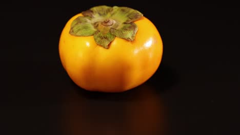 a persimmon rotates on a dark surface
