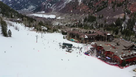 estación de esquí con edificios y mucha gente en un día de nieve, vista aérea ascendente