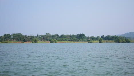scenic view of kabini river in nagarahole forest on a sunny day, surrounded by lush greenery.