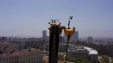 Toma-Panorámica-De-Paralaje-Del-Sistema-De-Poleas-Y-Engranajes-Encima-De-Una-Grúa-De-Elevación-De-Servicio-Pesado-En-Un-Sitio-De-Construcción-En-El-Oeste-De-Los-Ángeles,-California.