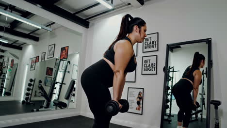 plus-size woman working out with dumbbells in a gym