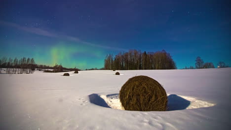 plano general del campo de invierno cubierto de nieve con balas de heno congeladas y aurora boreal mágica en el cielo nocturno brillante - lapso de tiempo