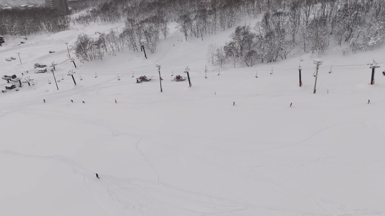 Tracking Shot of a skier traversing the mountains in Hokkaido, Japan near a ski lift.