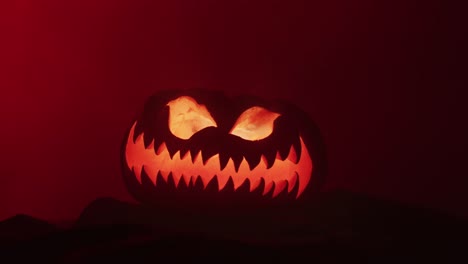 Video-of-halloween-carved-pumpkin-with-smoke-and-red-light-on-black-background