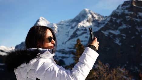 inspired female tourist in switzerland take photos of snowy mountain range