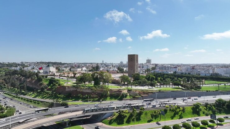 Ampio panorama aereo di Rabat, in Marocco, con la storica Torre di Hassan tra parchi verdi, strade moderne, traffico e lo skyline della capitale in espansione
