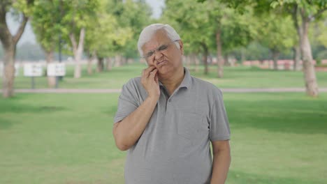 Indian-old-man-suffering-from-toothache-in-park