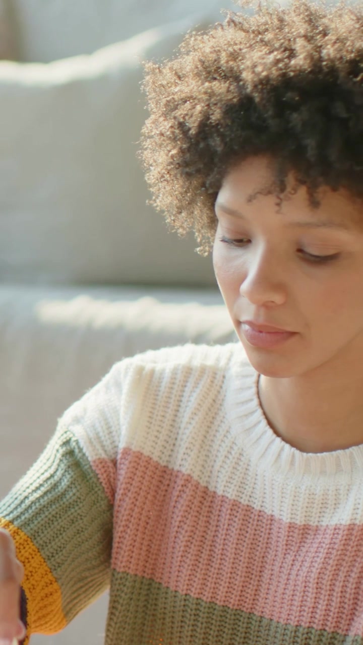Vertical video: Reaching polish woman in pale sweater steadying and painting friend's nails at home