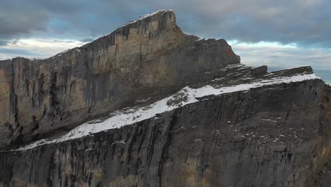 drone shot flying next to the edge of a massive cliff on top of a mountain in switzerland