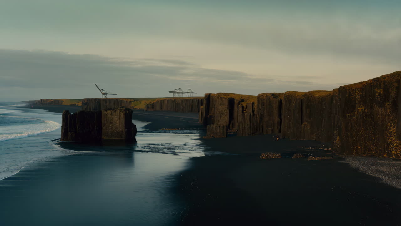 Dramatic black sand beach with basalt columns and ocean waves under a cloudy sky in Iceland