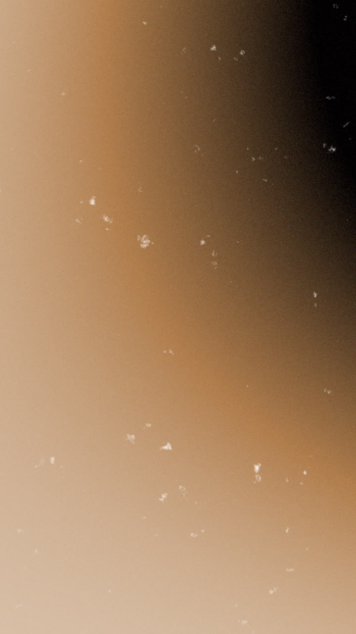 Particelle di polvere scintillanti fluttuanti su uno sfondo sfumato caldo