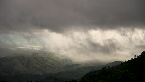 nubes sombrías se ciernen sobre un valle boscoso, creando una atmósfera dramática y misteriosa.
